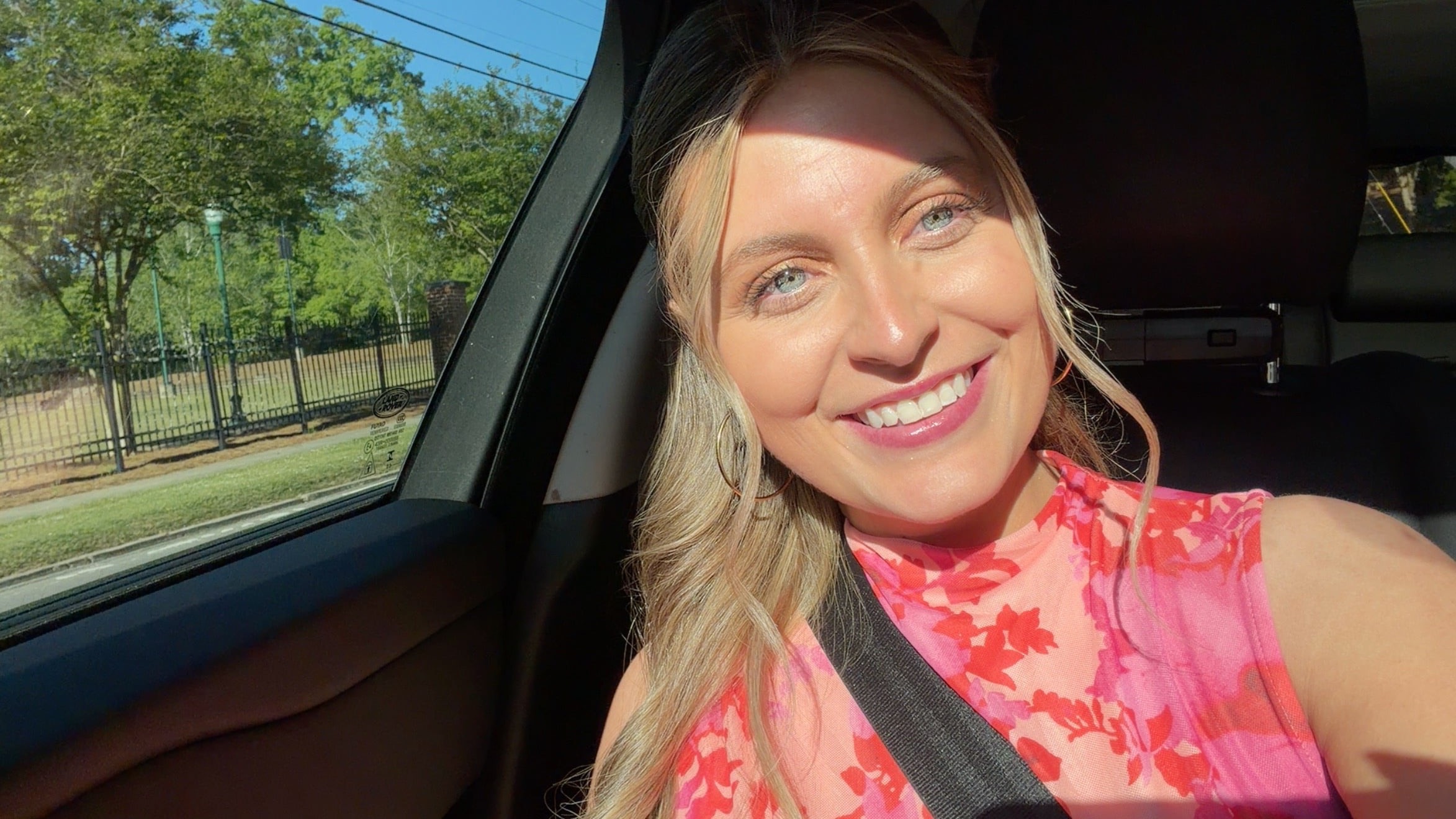 Tristin in a coral floral top, soft daylight selfie in a car